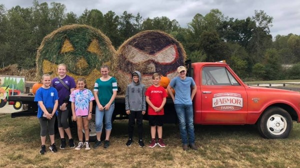 Kids getting a picture in front of pumpkin hay bales at Jaemor
